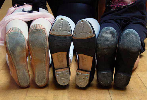 Three sets of feet with ballet, jazz and tap shoes on